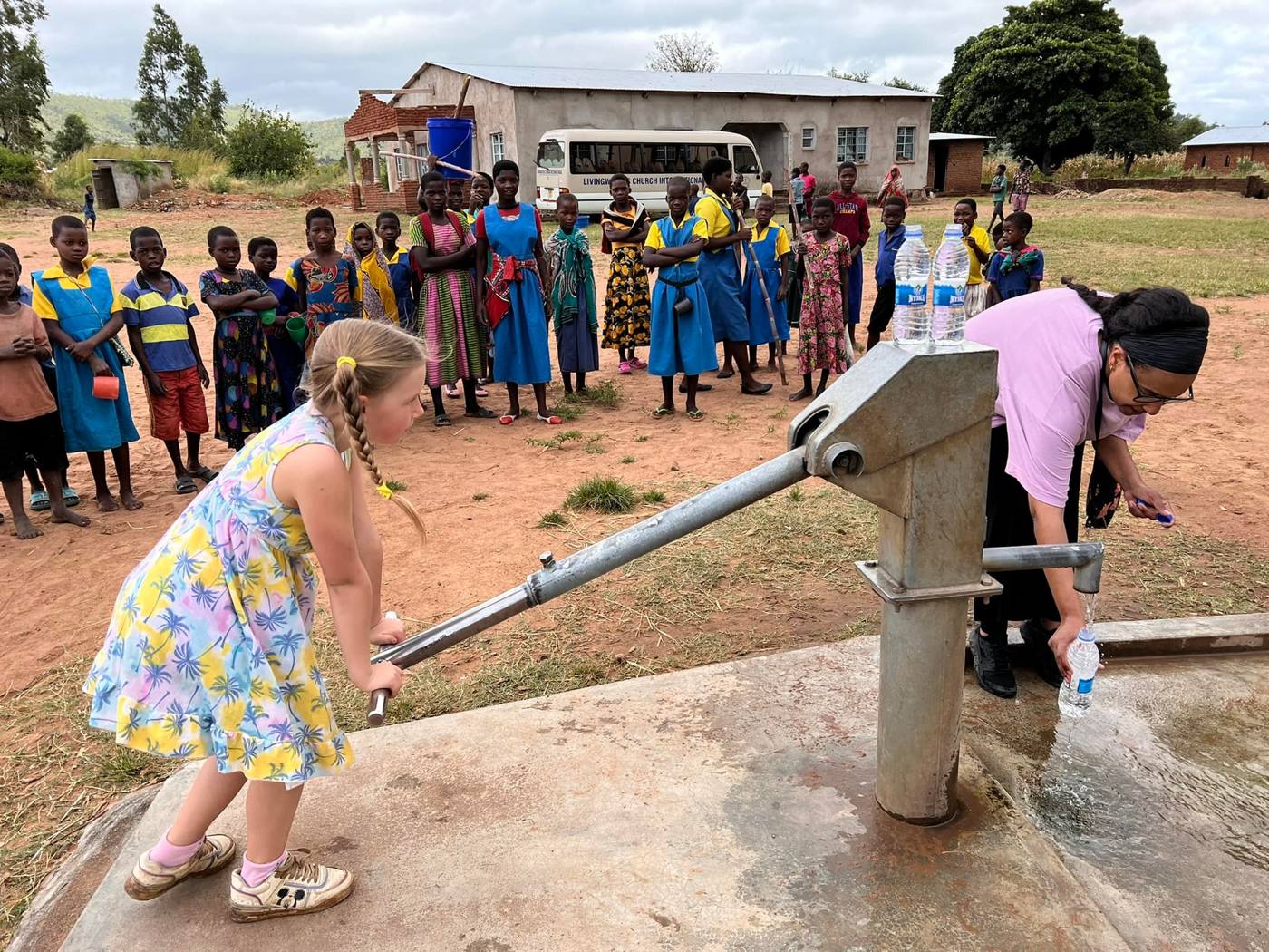 A girl pumping clean water at a village well in Malawi