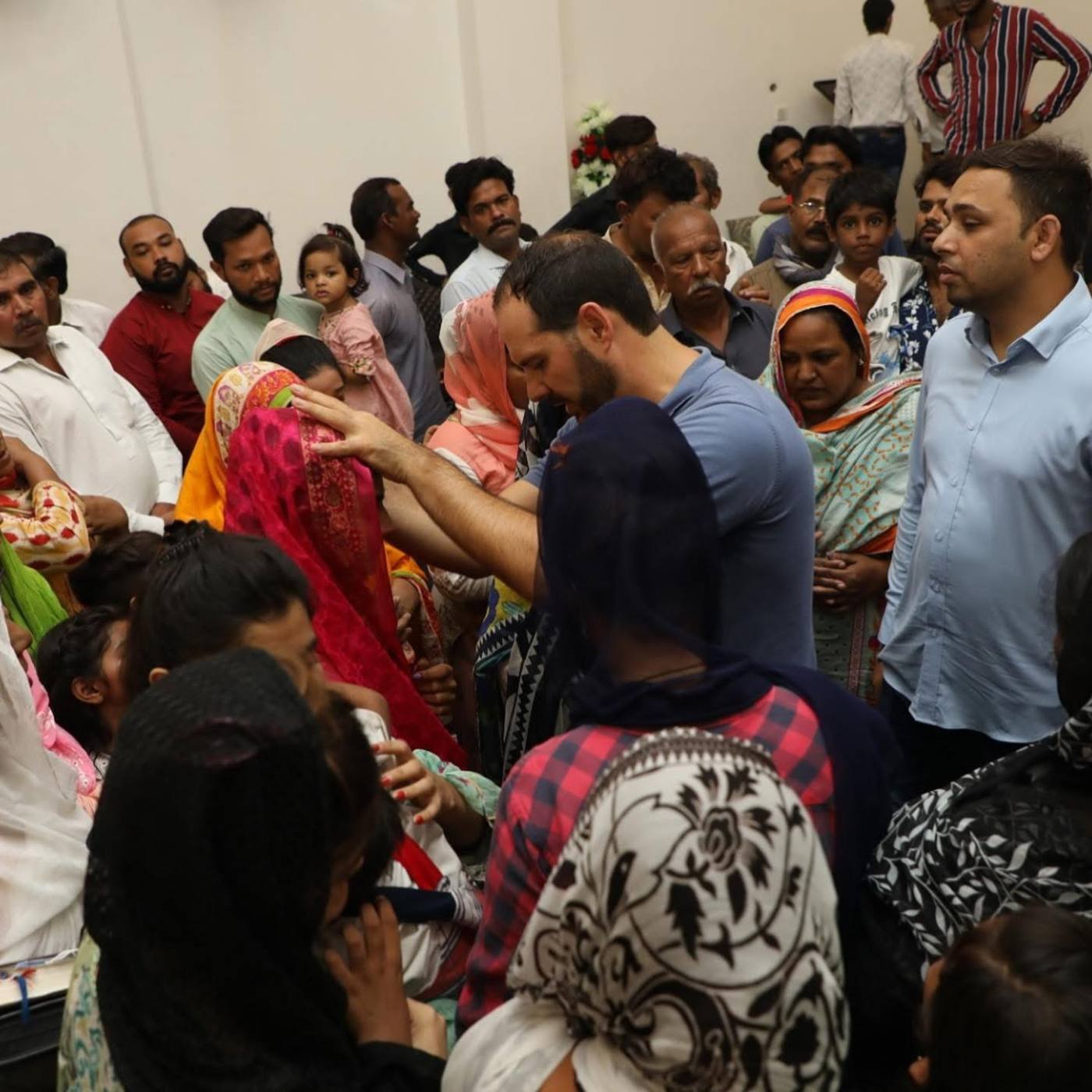 Praying for people in a crowded room in Pakistan