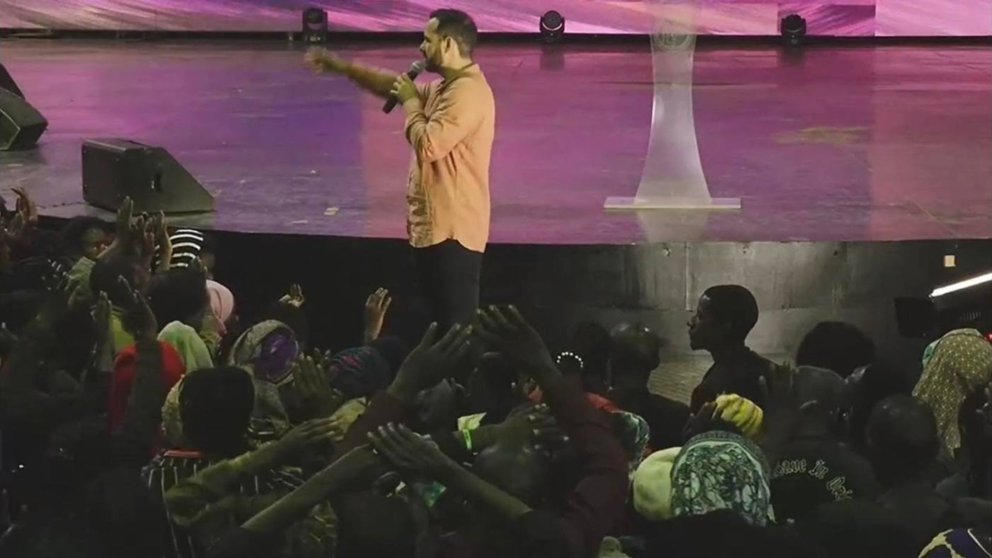 Preaching from the stage as the crowd reaches forward in Uganda